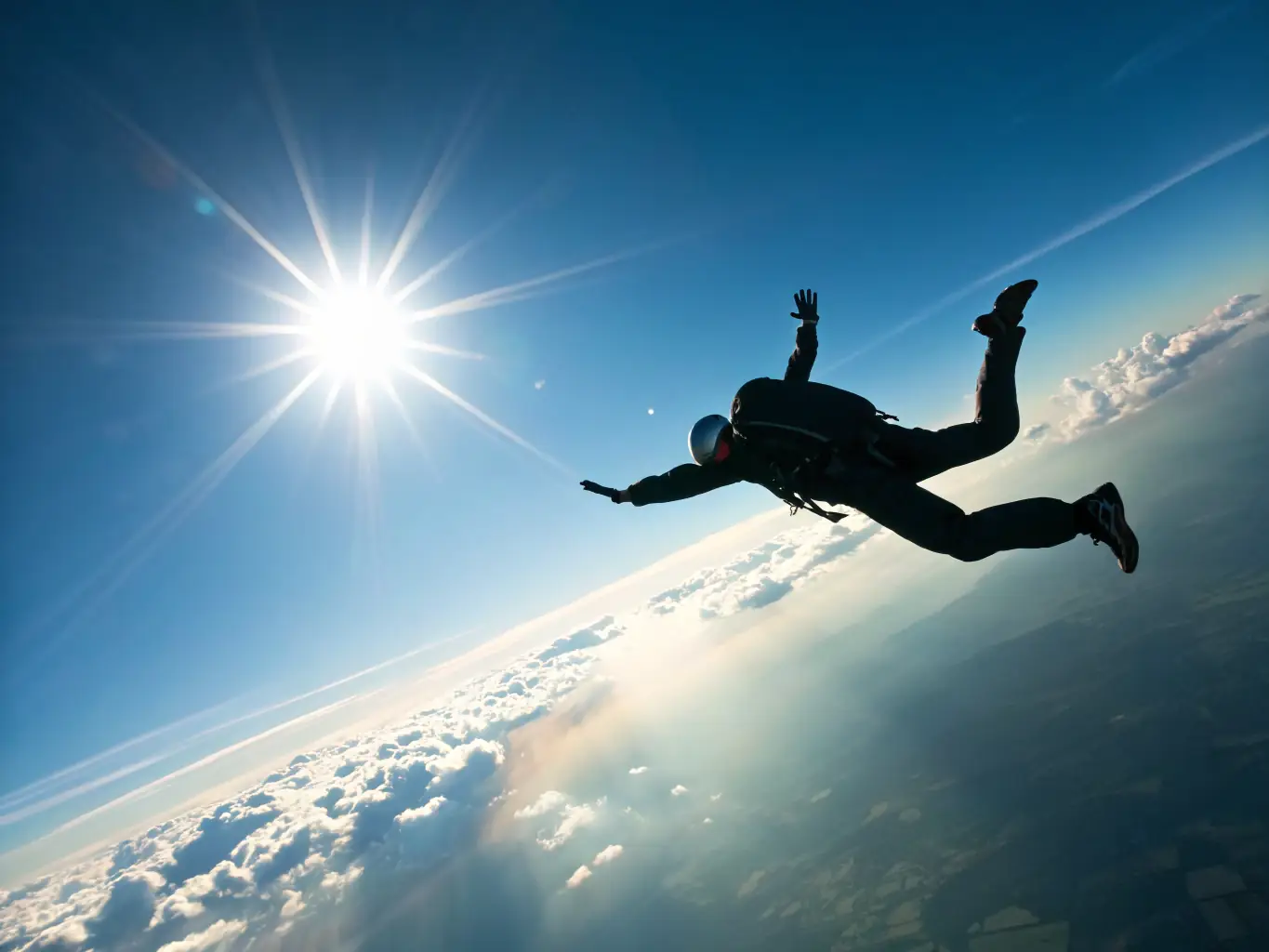 A smiling woman in a skydiving harness with an instructor, soaring through the blue sky with clouds in the background, representing the tandem skydiving experience offered by All in Flight.